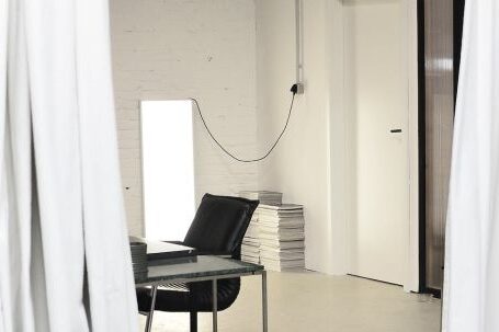 Creative Organization - Interior of spacious loft studio with meeting table and chairs surrounded by hanging white curtains