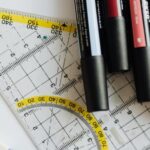Color Scheme. - Top view of various markers and plastic drawing triangle with marked lines and numbers placed on blank paper near eraser on wooden table in office