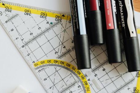 Color Scheme. - Top view of various markers and plastic drawing triangle with marked lines and numbers placed on blank paper near eraser on wooden table in office