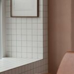 Small Space Decor Ideas - Blank frame hanging on tiled wall near window in small light room with soft brown leather armchair on floor at home
