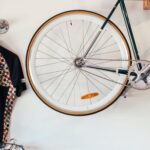 Stylish Storage. - Bicycles at white wall with various t shirts hanging on hangers on metal racks in light room with transport in storage
