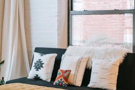 Interior Design - Light room interior with decorative cushions on soft couch against fabric bench on parquet at home