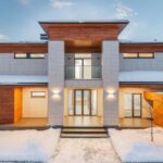 Luxury Properties - Backyard view of new modern luxurious cottage house with stone and wooden facade and illumination in winter countryside