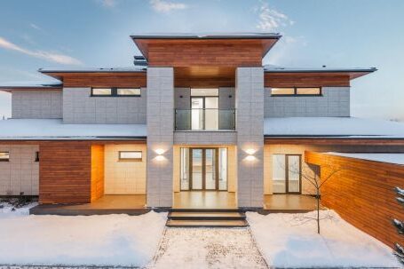 Luxury Properties - Backyard view of new modern luxurious cottage house with stone and wooden facade and illumination in winter countryside