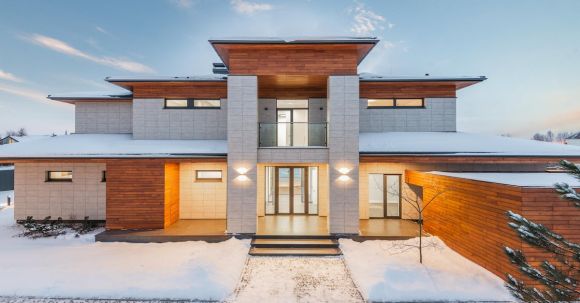 Luxury Properties - Backyard view of new modern luxurious cottage house with stone and wooden facade and illumination in winter countryside