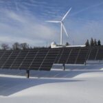 Renewable Energy - Solar Panels on Snow With Windmill Under Clear Day Sky