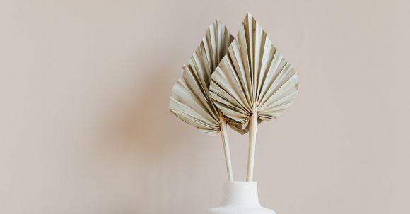 Unique Furniture - Decorative golden leaves in unique formed white vase placed on marble table against beige background