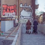 Neighborhood - Two People Walking on Bridge