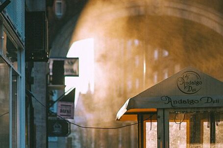 Neighborhood - Unrecognizable people walking along arched passage at sunrise