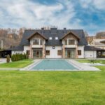 Luxury Properties - Exterior of contemporary residential cottage house with green lawn in yard under cloudy sky