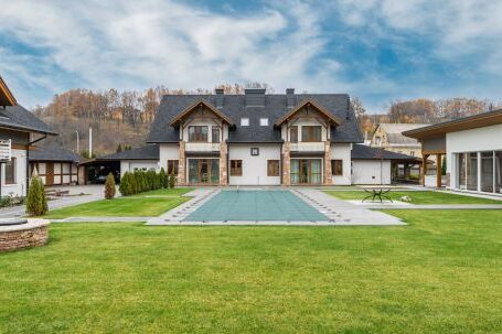 Luxury Properties - Exterior of contemporary residential cottage house with green lawn in yard under cloudy sky