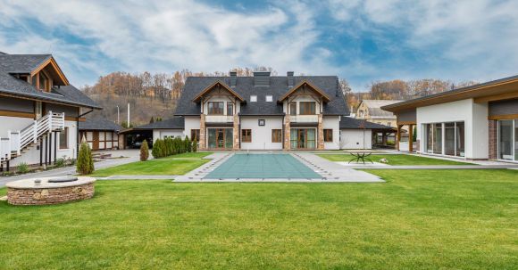 Luxury Properties - Exterior of contemporary residential cottage house with green lawn in yard under cloudy sky