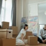 New Home - Man in Gray Long Sleeve Shirt Sitting Beside Woman in White Long Sleeve Shirt