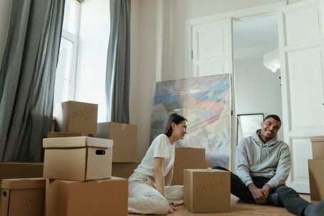 New Home - Man in Gray Long Sleeve Shirt Sitting Beside Woman in White Long Sleeve Shirt