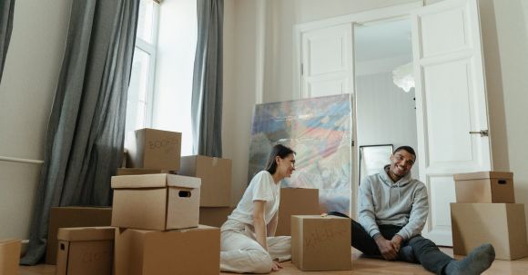New Home - Man in Gray Long Sleeve Shirt Sitting Beside Woman in White Long Sleeve Shirt