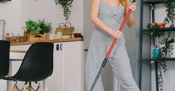 Housewife Washing Floor - Young carefree female in jumpsuit dancing while cleaning parquet with mop in light house room