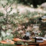 Picnic - Person Pouring Wine On A Glass Above A Wicker Basket