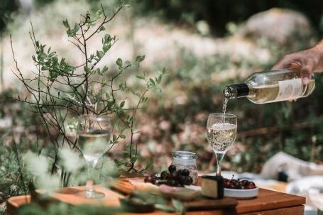 Picnic - Person Pouring Wine On A Glass Above A Wicker Basket