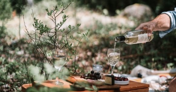 Picnic - Person Pouring Wine On A Glass Above A Wicker Basket