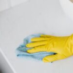 Bathroom Vanity - From above crop unrecognizable person with microfiber cloth wearing yellow rubber glove and cleaning white marble tabletop of vanity table with washbasin in bathroom