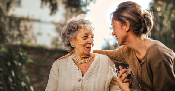 Garden Care - Joyful adult daughter greeting happy surprised senior mother in garden