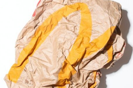 Reduce Waste - Top view of crumpled empty craft paper bag of fast food restaurant placed on white background illustrating recycle garbage concept