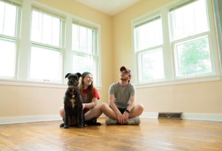 New Home - woman in gray shirt sitting on brown wooden floor