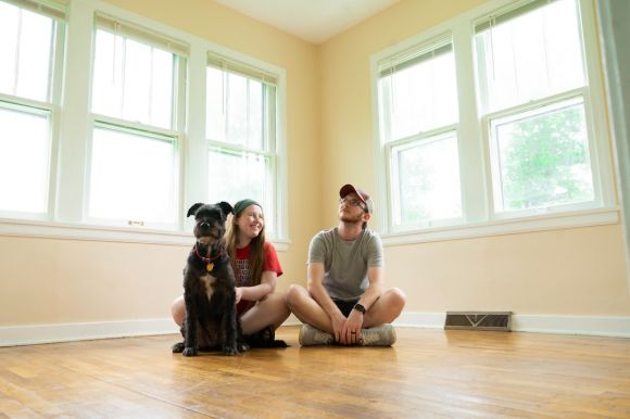 New Home - woman in gray shirt sitting on brown wooden floor