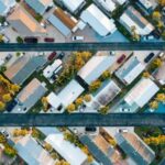 Neighborhood - Aerial view of many similar roofs of residential buildings with growing trees and parked cars near narrow asphalt roads in contemporary town in daylight