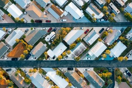 Neighborhood - Aerial view of many similar roofs of residential buildings with growing trees and parked cars near narrow asphalt roads in contemporary town in daylight