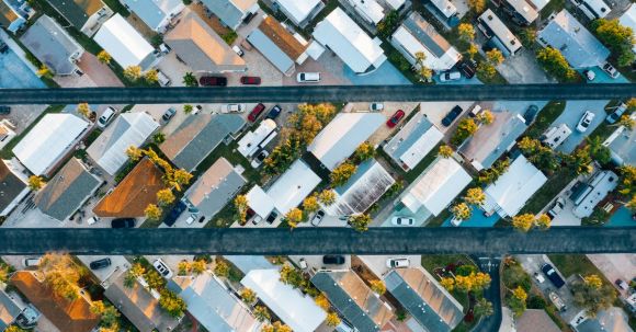 Neighborhood - Aerial view of many similar roofs of residential buildings with growing trees and parked cars near narrow asphalt roads in contemporary town in daylight