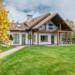 Luxury Properties - Exterior of residential suburban cottage with balcony surrounded with lush green plants and trees
