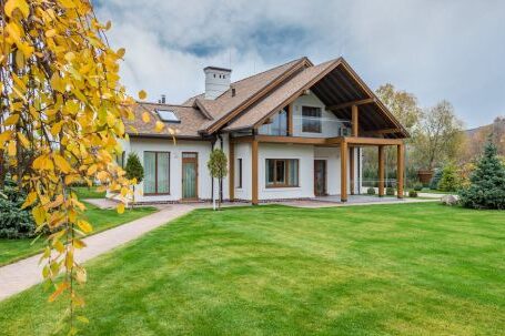 Luxury Properties - Exterior of residential suburban cottage with balcony surrounded with lush green plants and trees