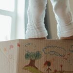 New Home - Person in White Pants and White Socks Standing Beside Brown Cardboard Box