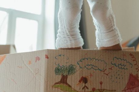 New Home - Person in White Pants and White Socks Standing Beside Brown Cardboard Box