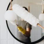 Cleaning - Crop woman dusting lamp during housework
