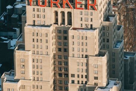 Neighborhood - Drone view of modern multistory hotel located on street with residential houses in megapolis with bright sunlight in New York