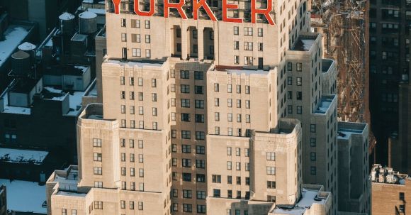 Neighborhood - Drone view of modern multistory hotel located on street with residential houses in megapolis with bright sunlight in New York