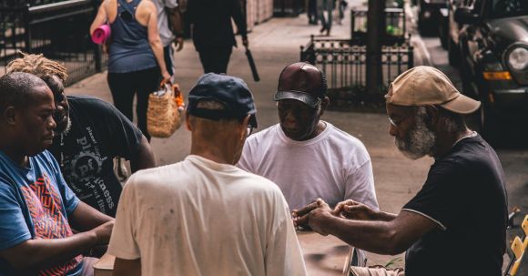 Neighborhood - Men Sitting Beside Table on Pathway Near People Walking Beside Rail