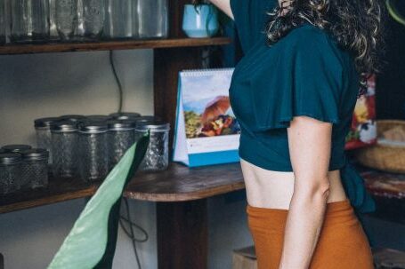 Sustainable Shopping - Woman Picking Up a Cup on Brown Wooden Shelf