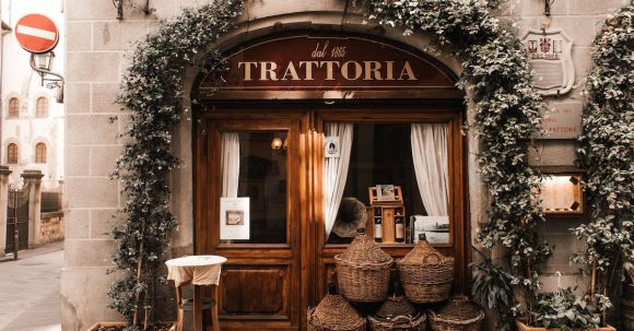 Neighborhood - Exterior of cozy Italian restaurant with wooden door and entrance decorated with plants