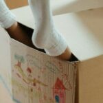 New Home - Person Wearing White Socks on Brown Cardboard Box