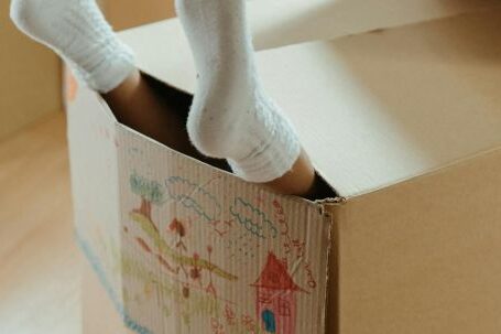 New Home - Person Wearing White Socks on Brown Cardboard Box