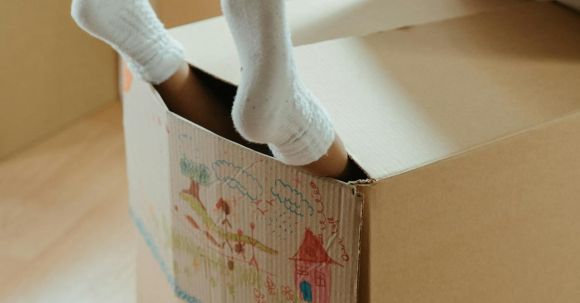 New Home - Person Wearing White Socks on Brown Cardboard Box