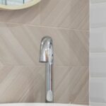 Luxury Properties - Interior of light modern restroom with sink and faucet on cabinet under mirror on tile wall