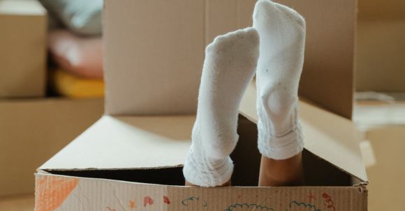 New Home - Person in White Socks Standing on Brown Cardboard Box