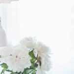 Home - White Peonies in Clear Glass Vase Centerpiece Near a White Ceramic Mug Closeup Photography