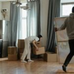 New Home - Man in Gray Hoodie Standing Near White Window Curtain