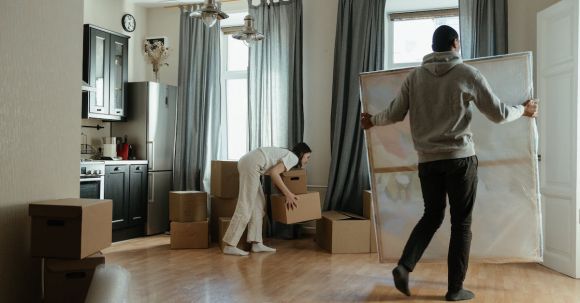 New Home - Man in Gray Hoodie Standing Near White Window Curtain